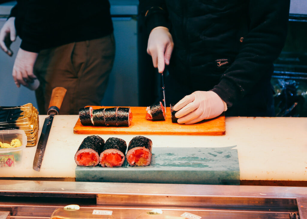Chef slicing a freshly made sushi roll at the counter